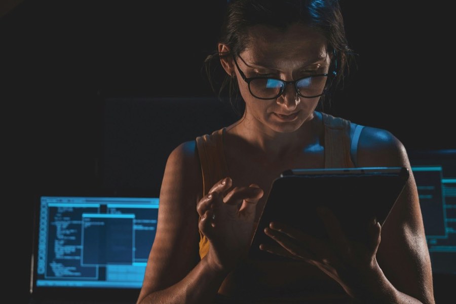 A worker lit by screens late at night, working under monitoring